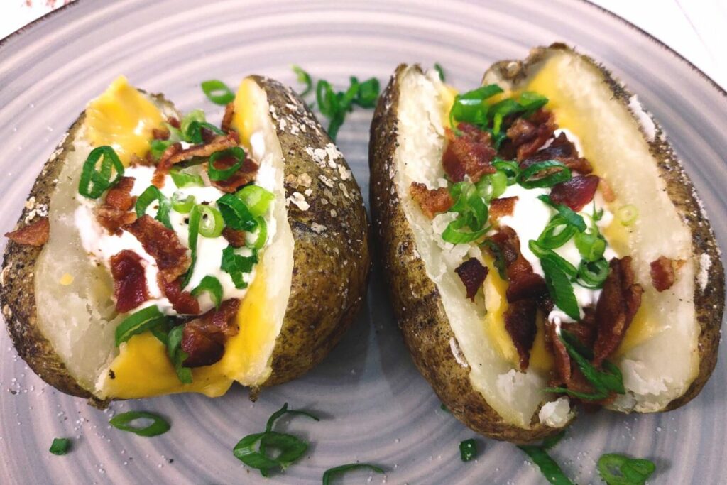 loaded air fryer baked potatoes with cheese, bacon, sour cream, and onions