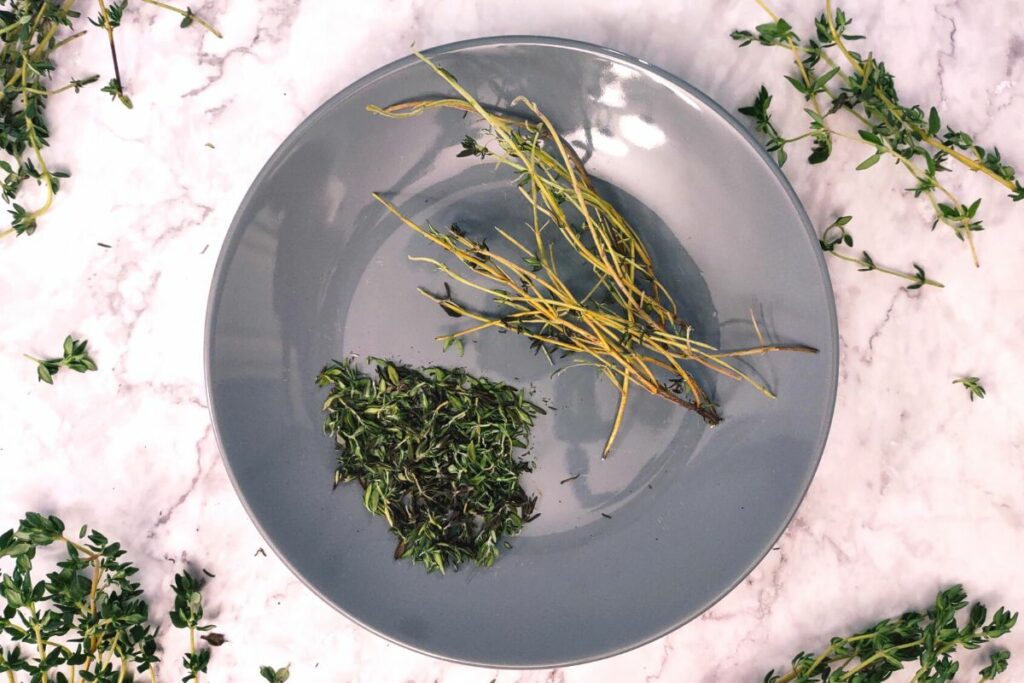dry thyme leaves separated from stems on a plate
