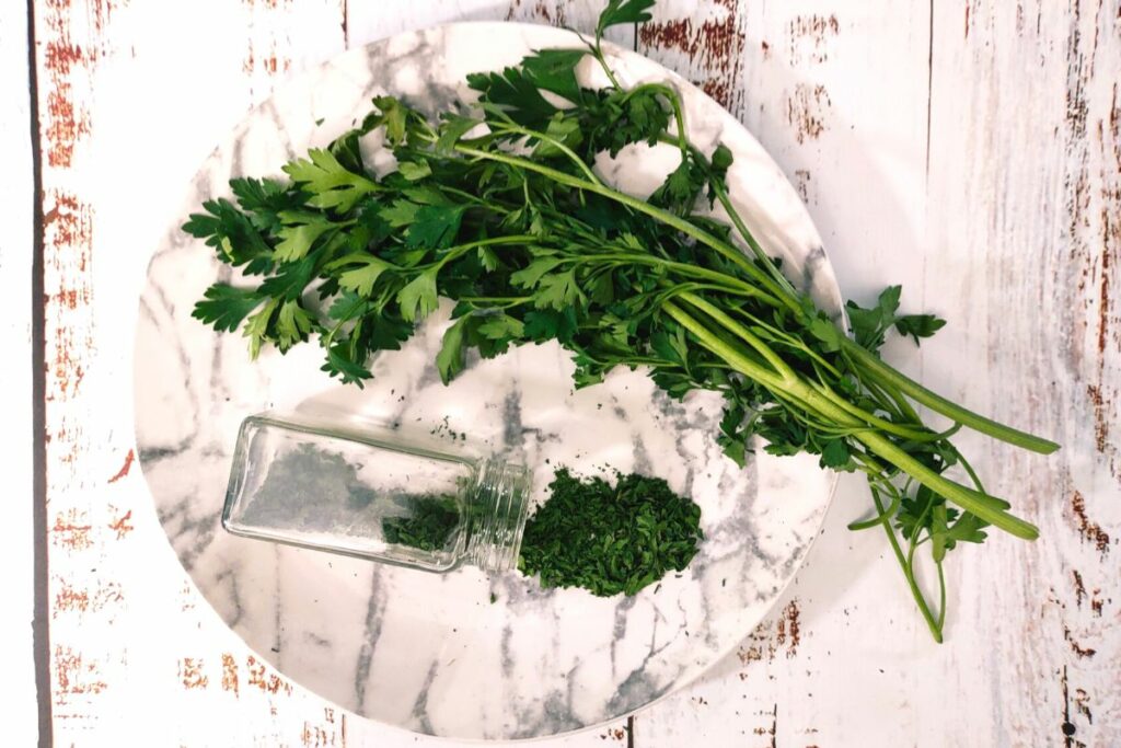 air fryer parsley sprigs on a plate with dried leaves and glass jar