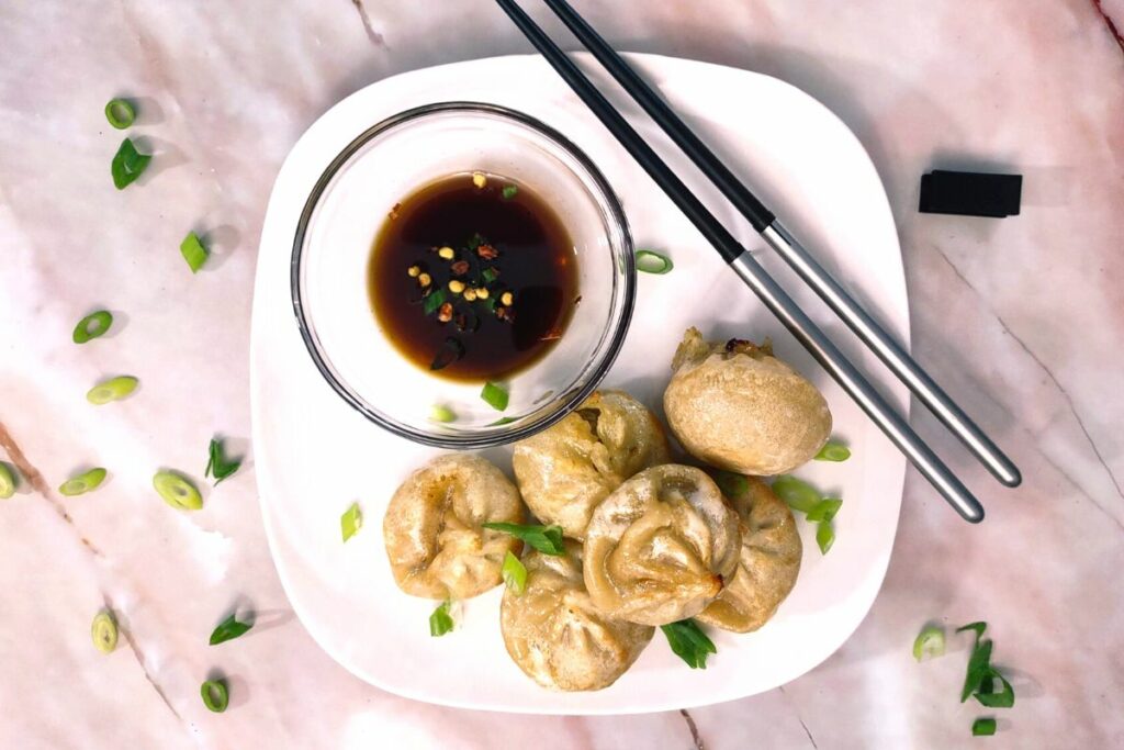 air fryer bibigo dumplings on a plate with soy sauce and chopsticks
