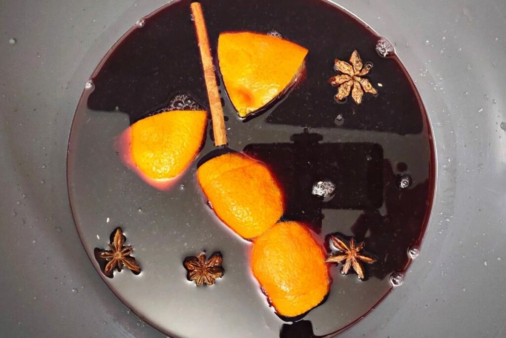 4 orange quarters, star anise, and cinnamon sticks in mulled wine