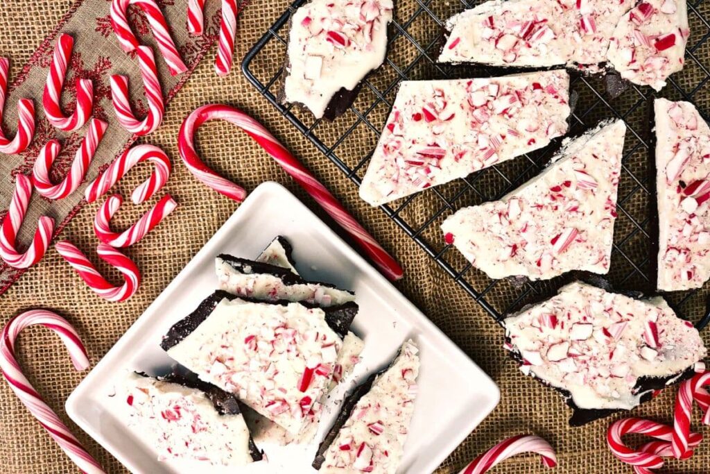 overhead view of peppermint bark broken into pieces with whole candy canes in the top left corner