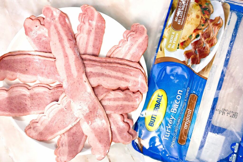 fresh turkey bacon on a plate next to its packaging