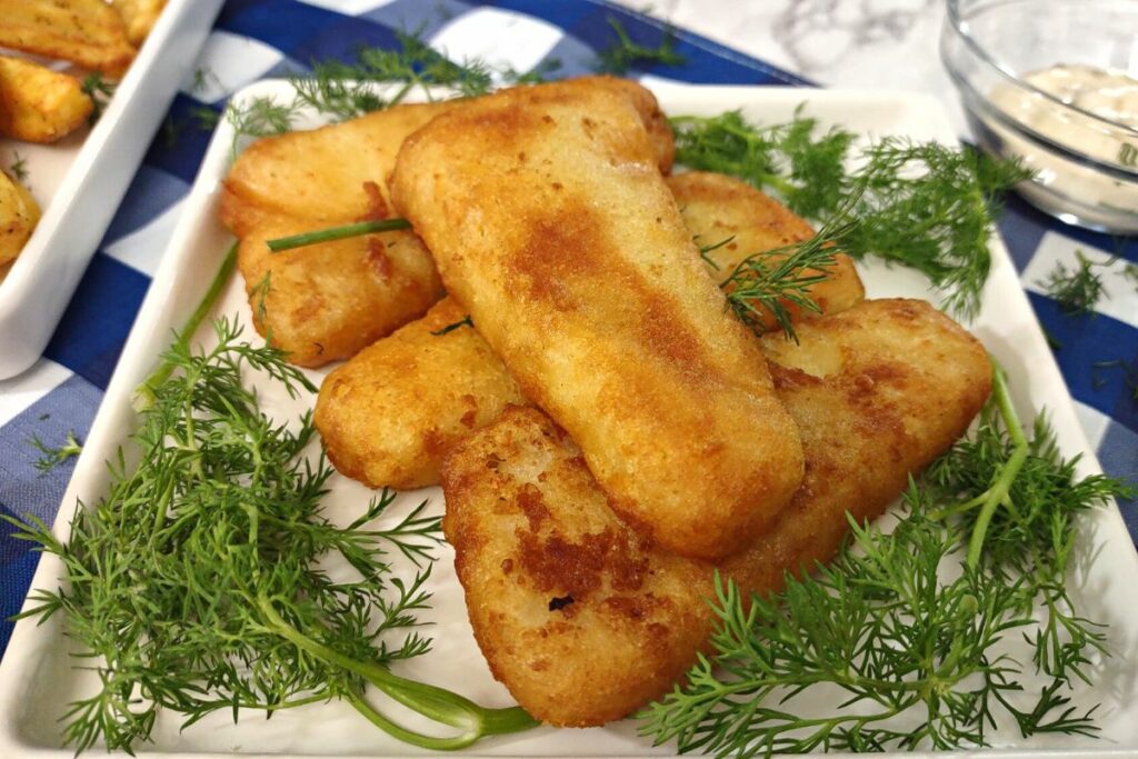 closeup of air fried fish fillets on a plate with fresh dill sprigs