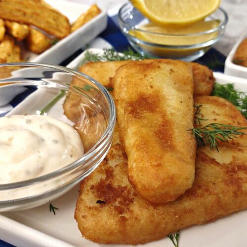 crunchy fish fillet with tartar sauce and side dishes in the background