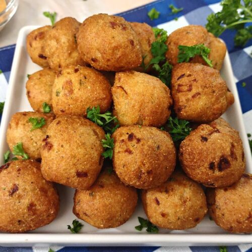 golden brown frozen hush puppies cooked in the air fryer stacked on a white square plate