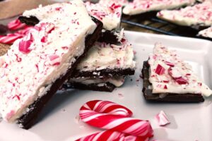 closeup of peppermint bark pieces on a plate laying on top of each other with broken mini candy cane pieces