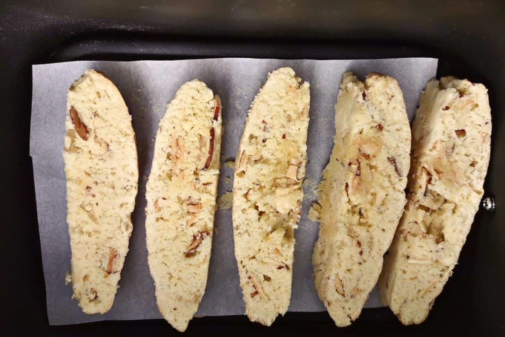 partially cooked biscotti slices in an air fryer basket