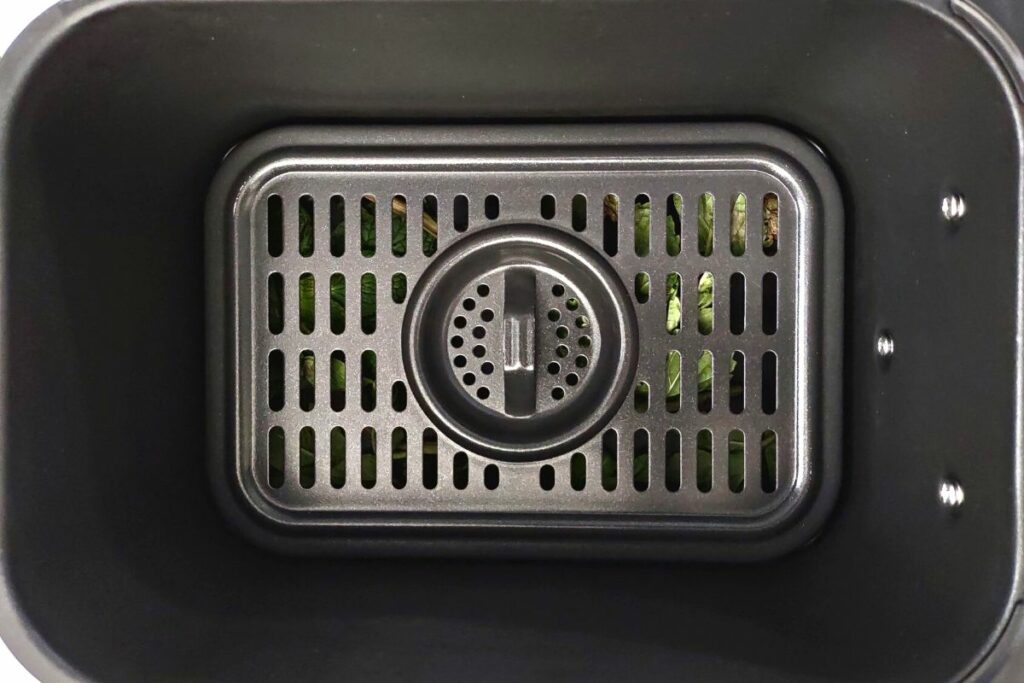 fresh mint in the bottom of an air fryer basket covered with a rack