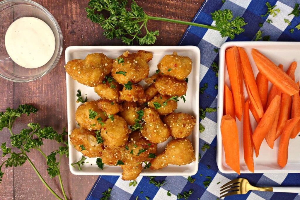 overhead view of air fryer buffalo cauliflower wings on a plate with carrots and ranch to the sides