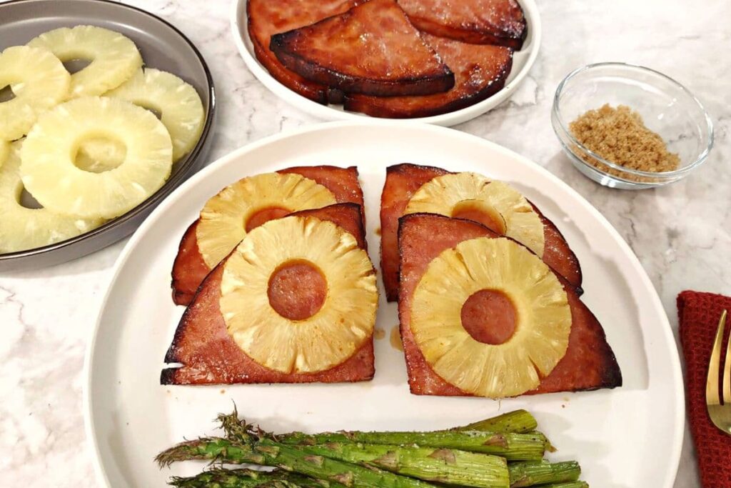 air fryer ham steak with pineapple slices and asparagus on a plate