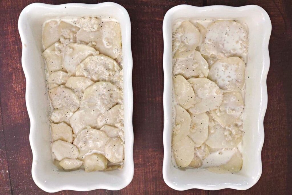 overhead view of scalloped potatoes in two rectangle casserole dishes covered in liquid cream mixture