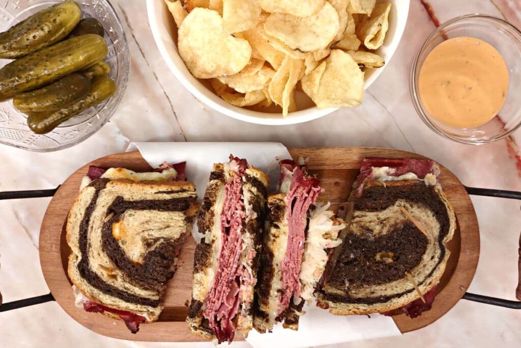 overhead view of air fried reuben sandwich cut in half with potato chips, pickles, and thousand island dressing