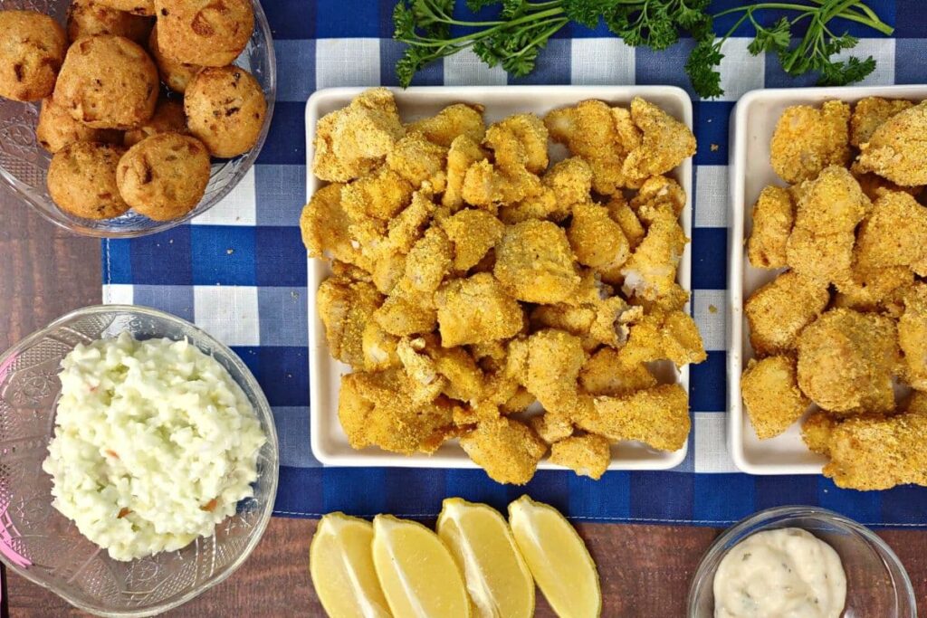 overhead view of crispy air fryer catfish nuggets on square plates on a blue checkerboard tablecloth
