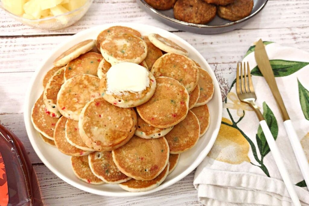 plate full of frozen mini confetti pancakes with a pad of butter on top