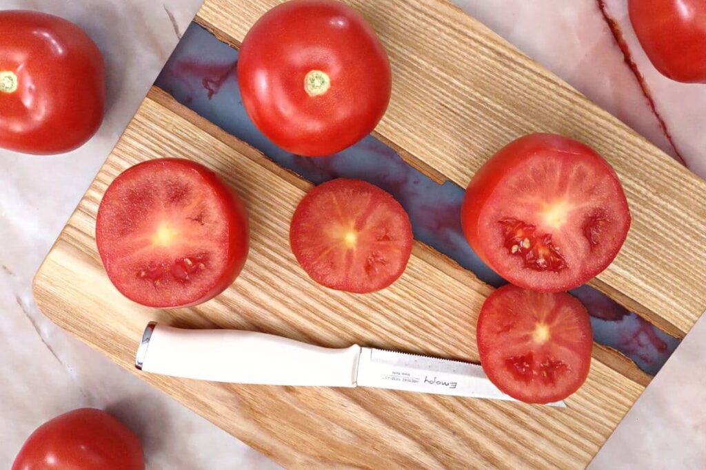 using a serrated knife cut the tops off each tomato