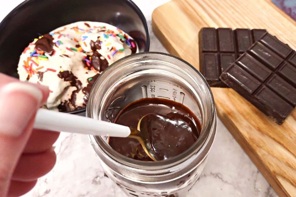 dipping a spoon inside a jar of melted homemade chocolate sauce
