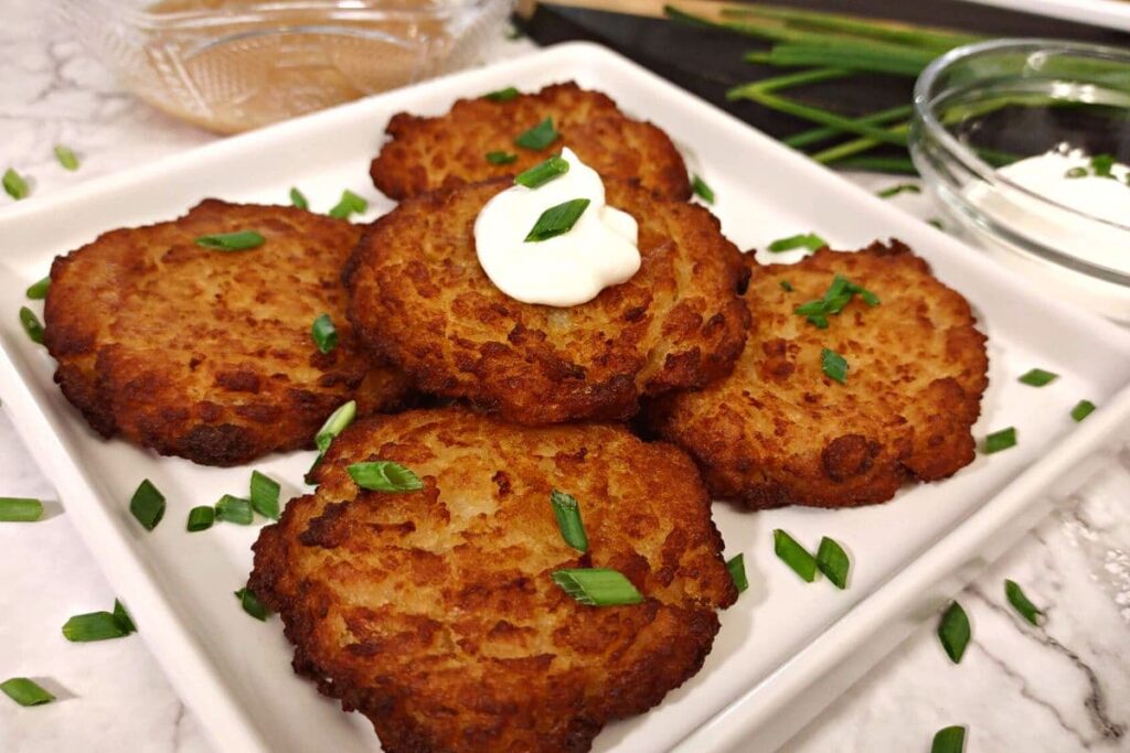 trader joe's potato latkes on a square plate with sour cream on top