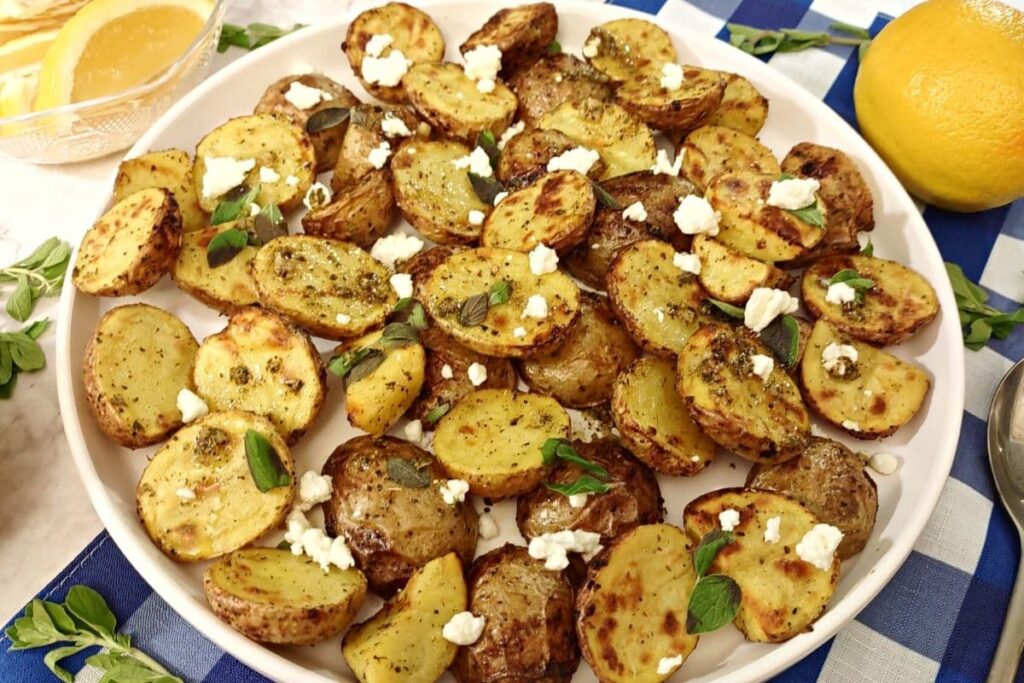 air fryer greek potatoes on a plate with feta cheese on top and lemons for decoration