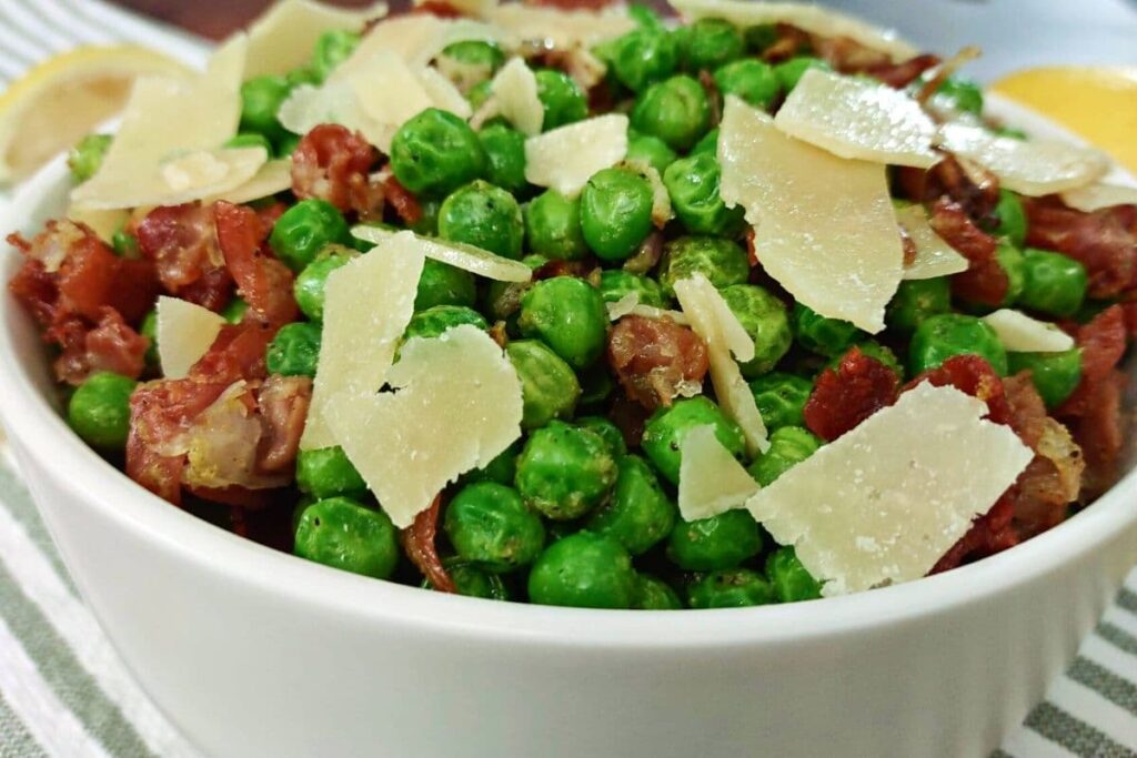 closeup of a bowl of air fryer peas and prosciutto with parmesan cheese on top