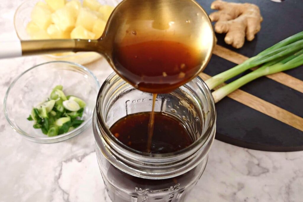 homemade teriyaki sauce dripping off a spoon into a jar