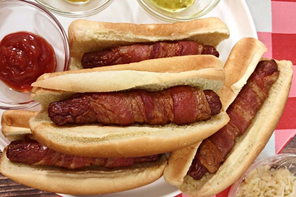 air fryer bacon wrapped hot dogs stacked up on a plate