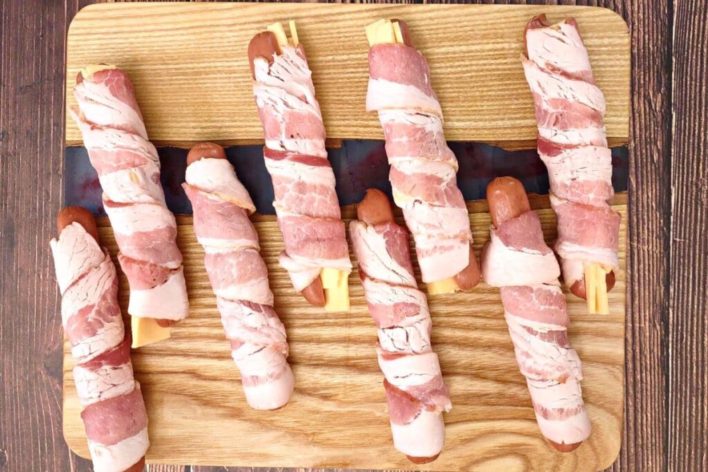 carefully wrap bacon around hot dogs