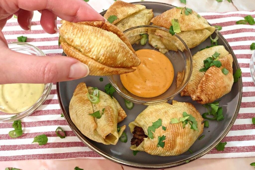 dipping air fried taco stuffed shell in chipotle sauce