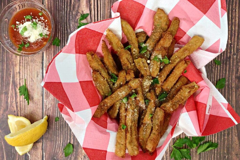 overhead view of air fryer eggplant fries in a basket with lemon and marinara on the side