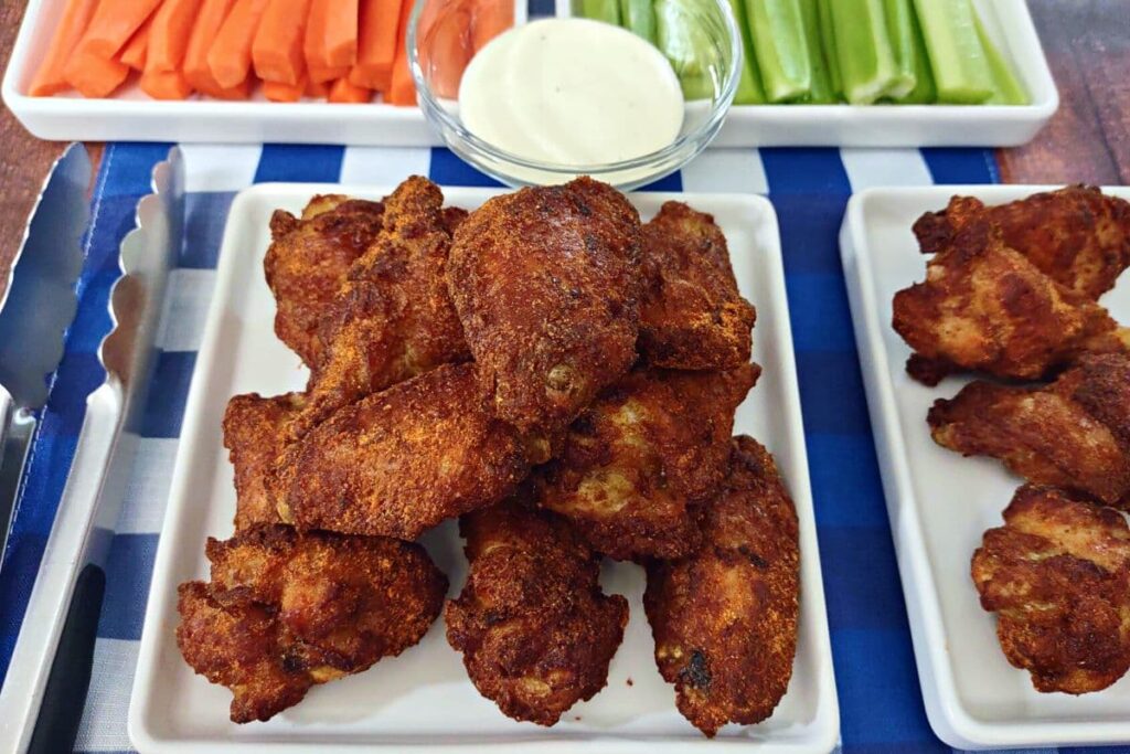 stack of air fryer frozen chicken wings on a plate with ranch and vegetables