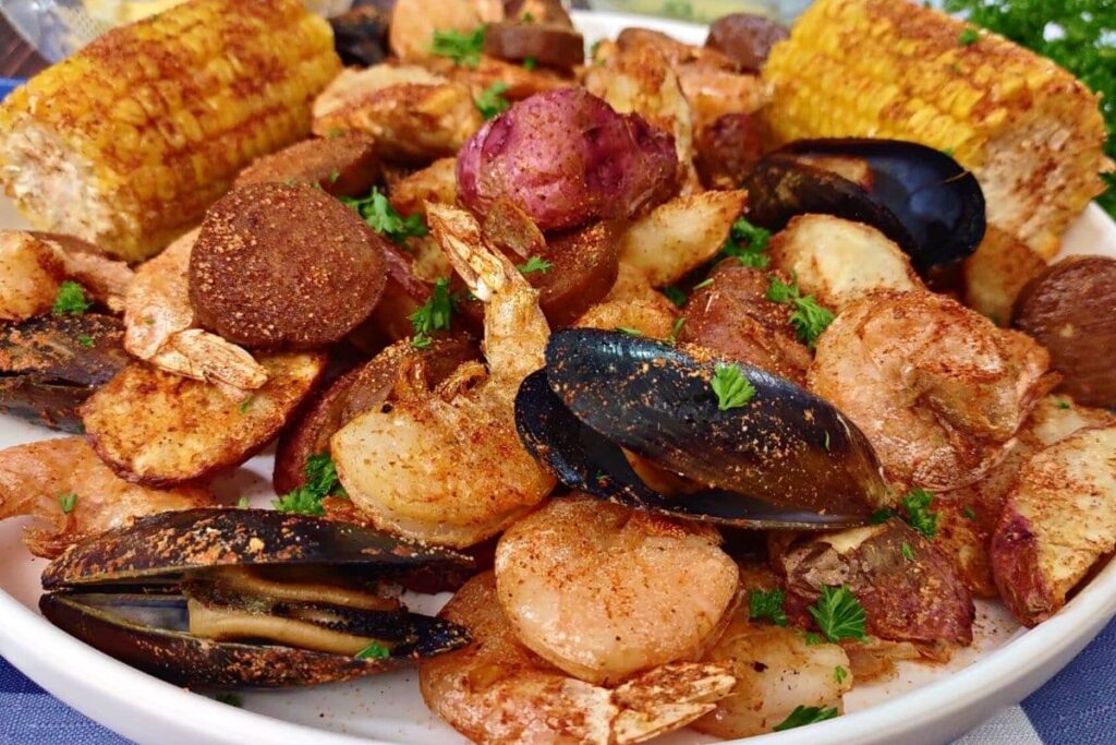 closeup of air fryer seafood boil with mussels, shrimp, sausage, and corn