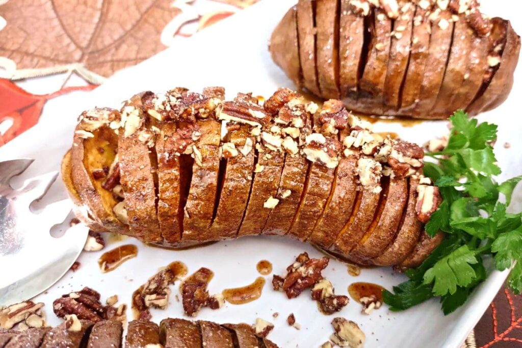 hasselback sweet potatoes with pecans and maple syrup glaze on a plate