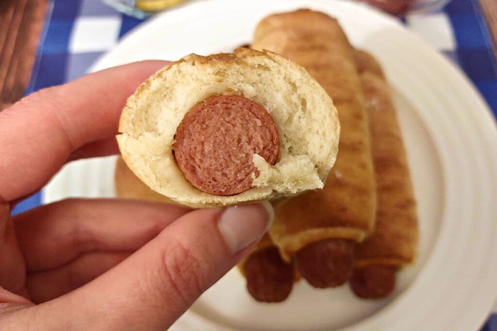 holding up a cross section of a nathan's pretzel dog