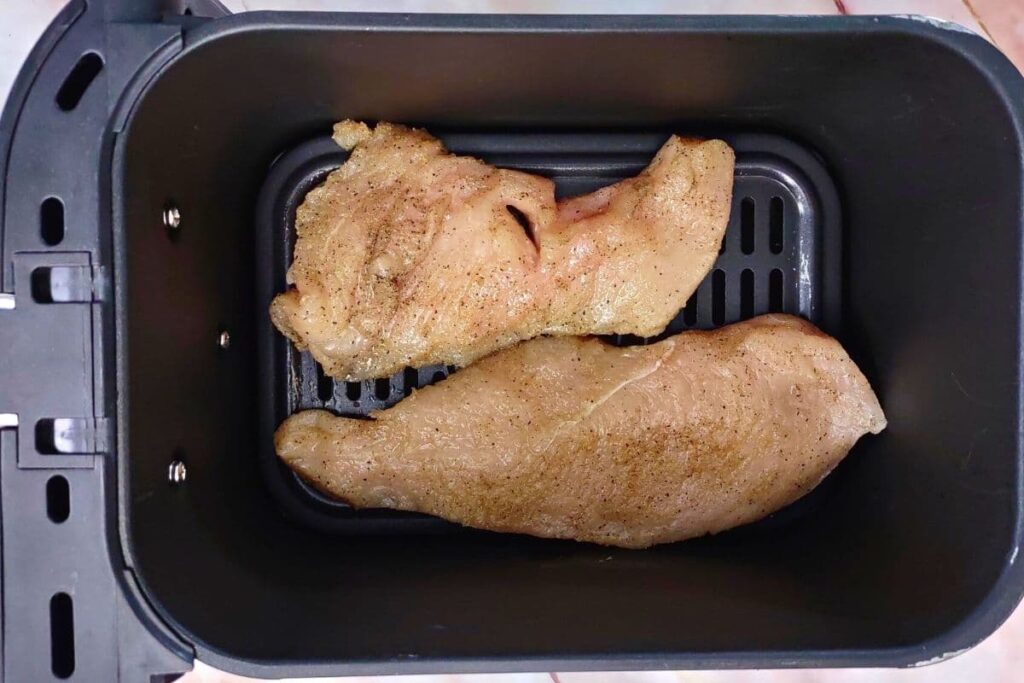 place seasoned chicken in air fryer basket