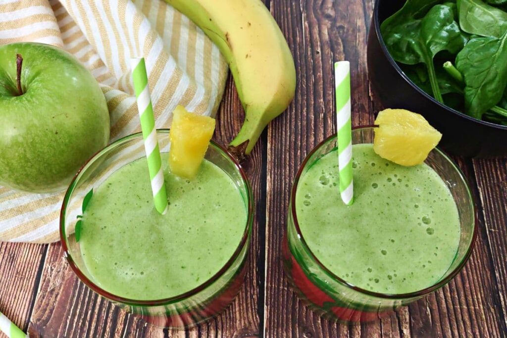 two glasses of fresh green apple smoothie drinks with striped straws