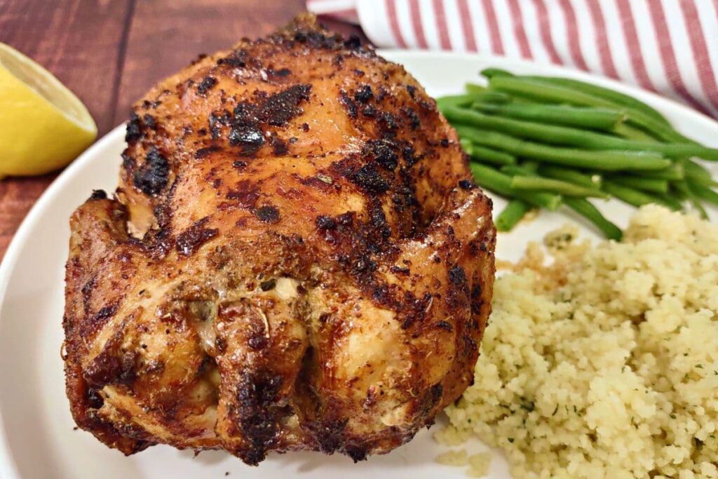 closeup of an air fried cornish hen on a plate with couscous and green beans