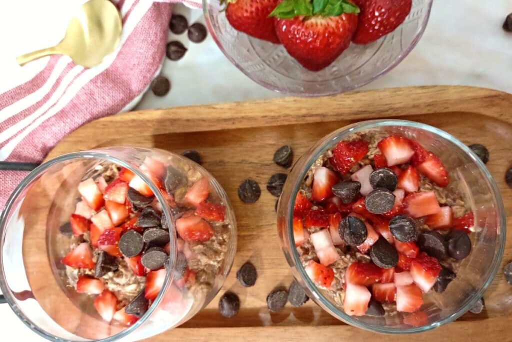 glasses of overnight oats with strawberries and chocolate on top