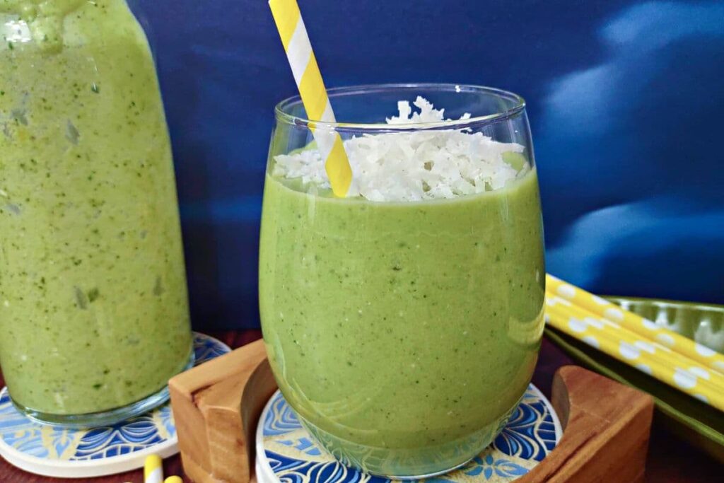 green pina colada smoothie in a glass with a striped straw