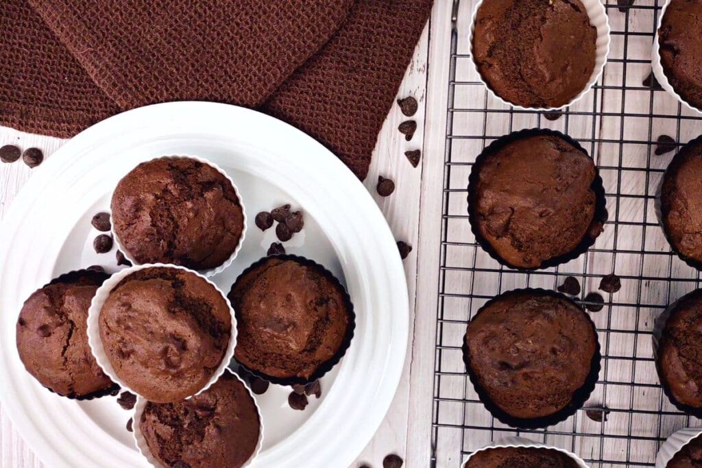 overhead view of air fryer double chocolate muffins stacked on a plate and wire rack