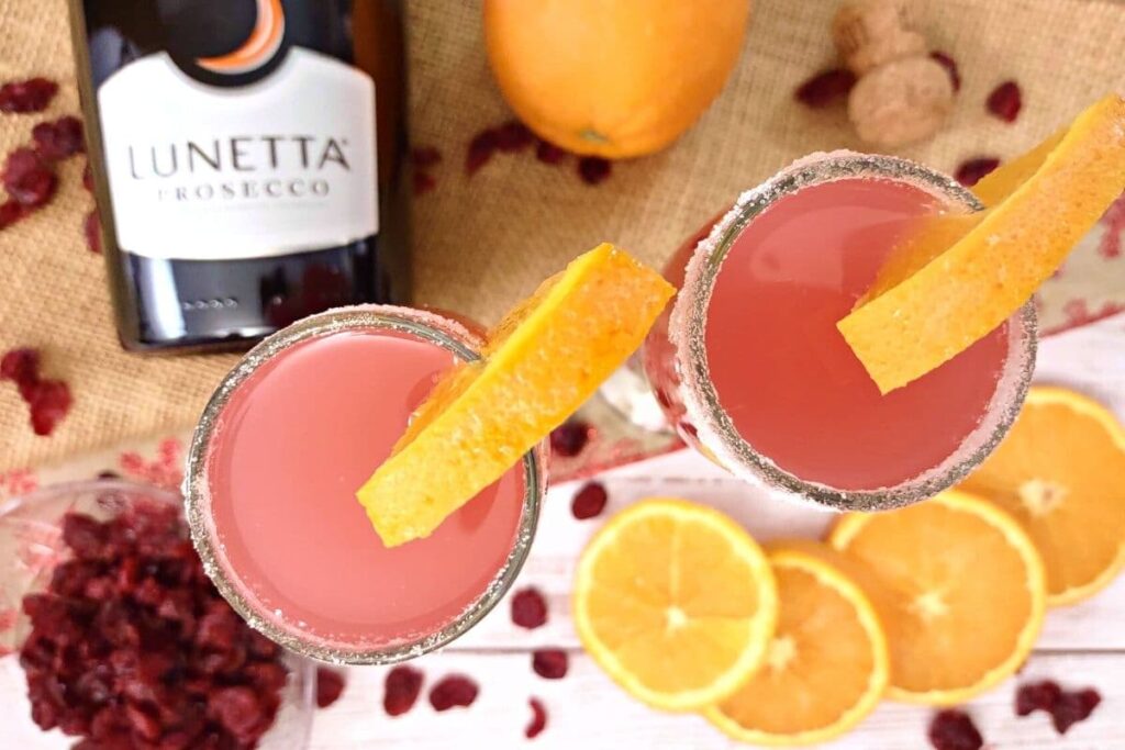 overhead view of cranberry orange mimosas with orange slices and cranberry