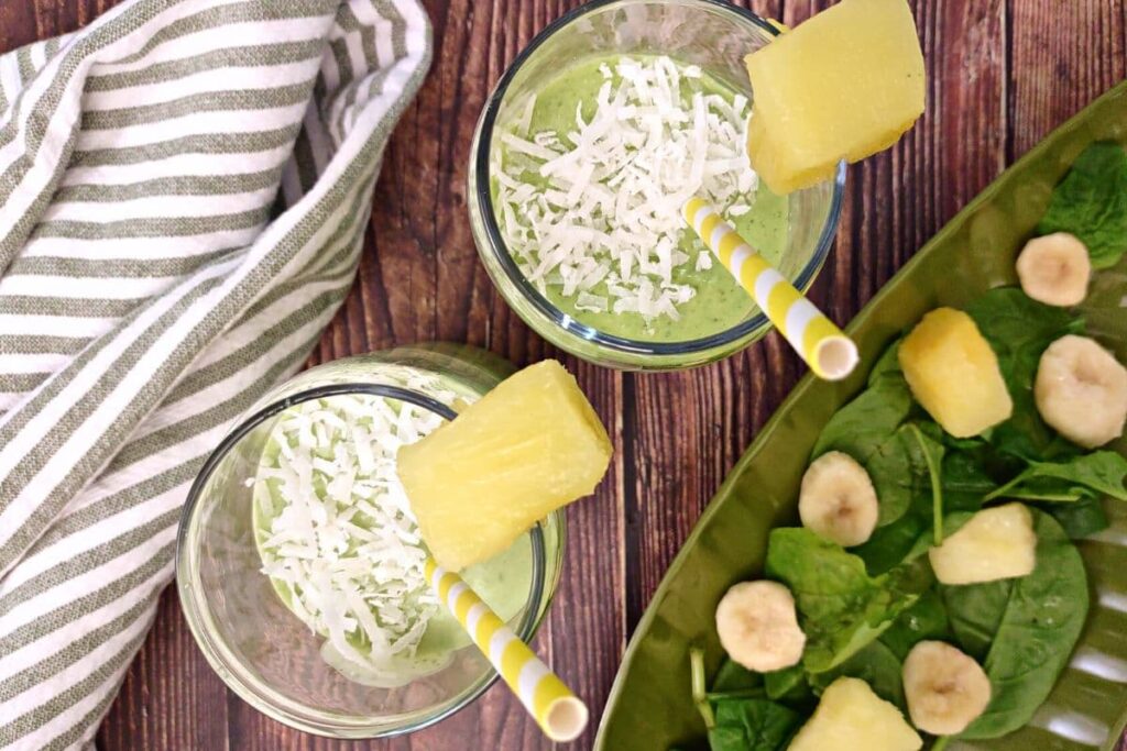 overhead view of green pina colada smoothies with pineapple chunks