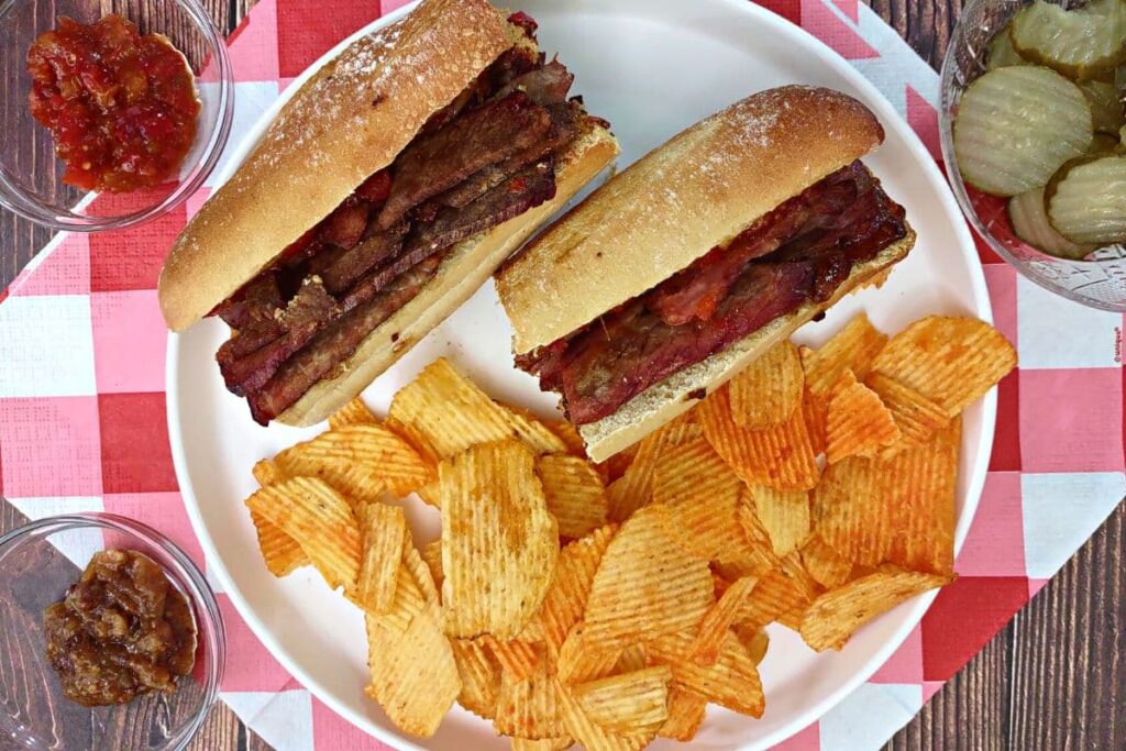 overhead view of two air fryer brisket sandwiches on a plate with bbq chips