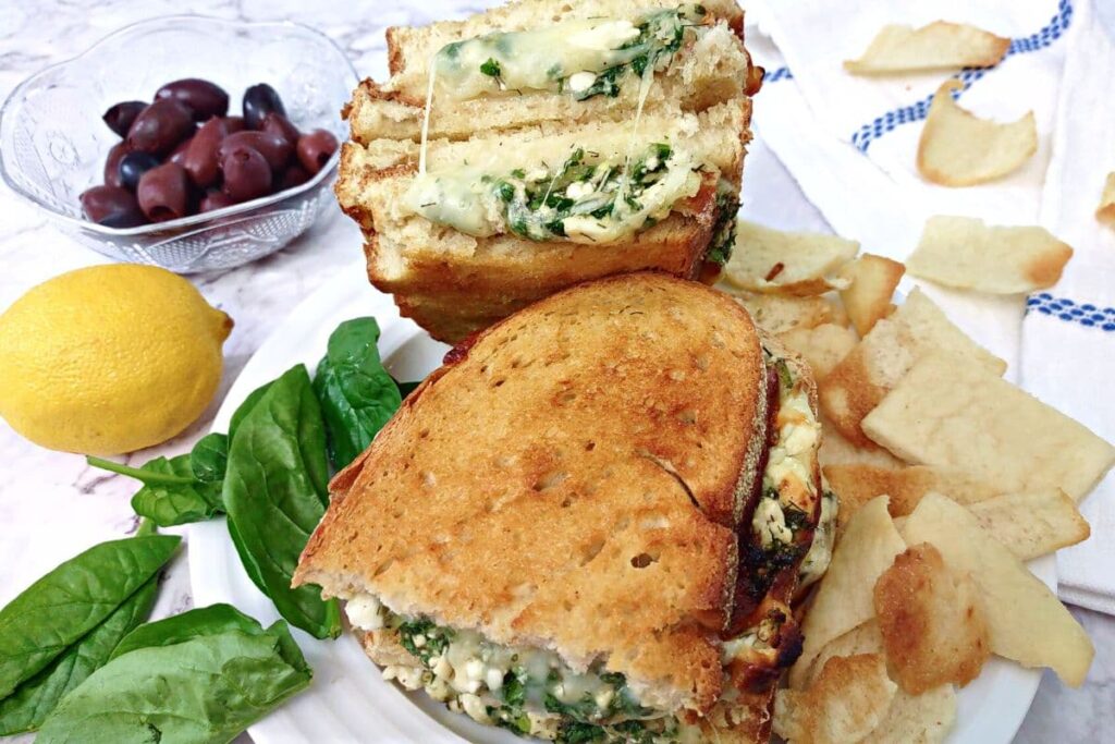 spanakopita grilled cheese halves on a plate with pita chips