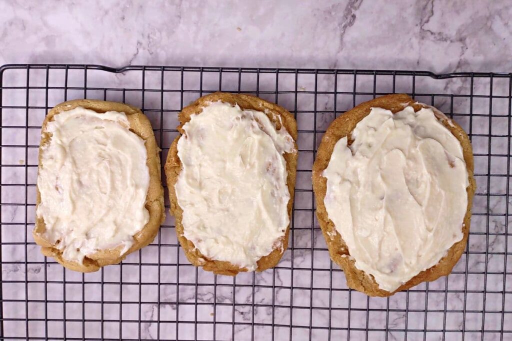 spread the cream cheese frosting over the cooled cookies
