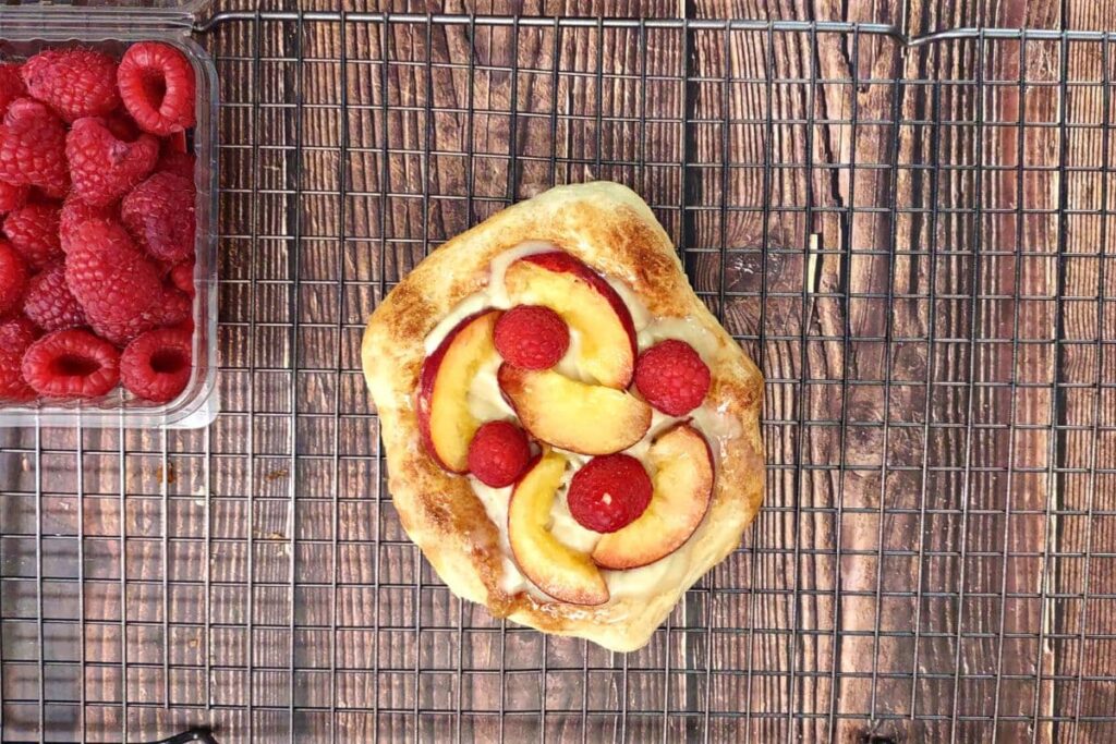top pizza with peach slices and raspberries