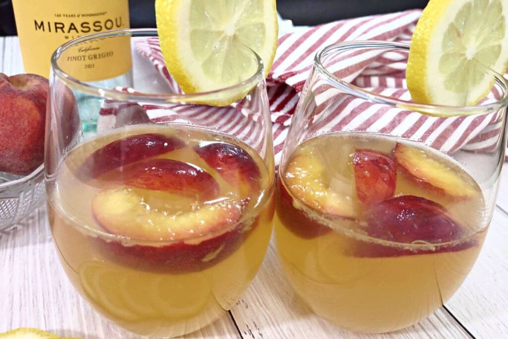 two glasses of ginger peach sangria with lemon slices