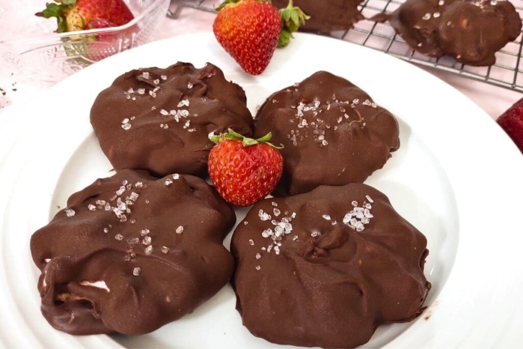 chocolate covered yogurt clusters on a plate with a fresh strawberry in the center