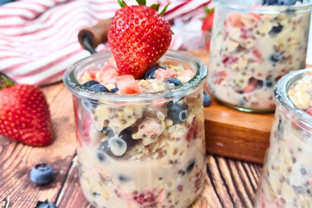 closeup of jar filled with strawberry blueberry overnight oats with a fresh strawberry on top
