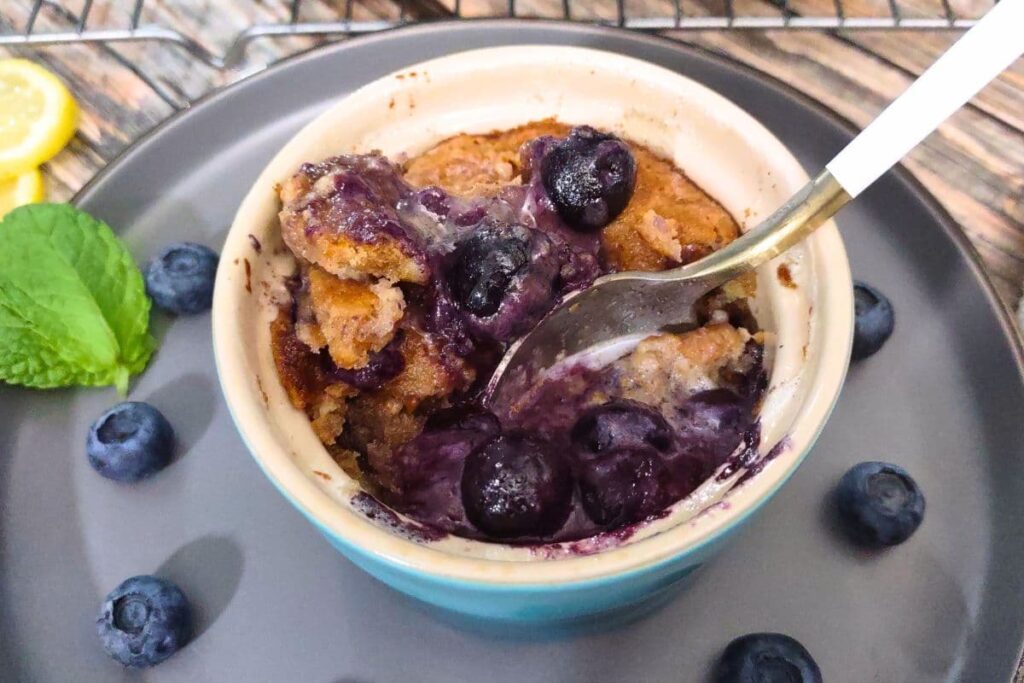 dipping a spoon into a bowl of air fryer blueberry cobbler