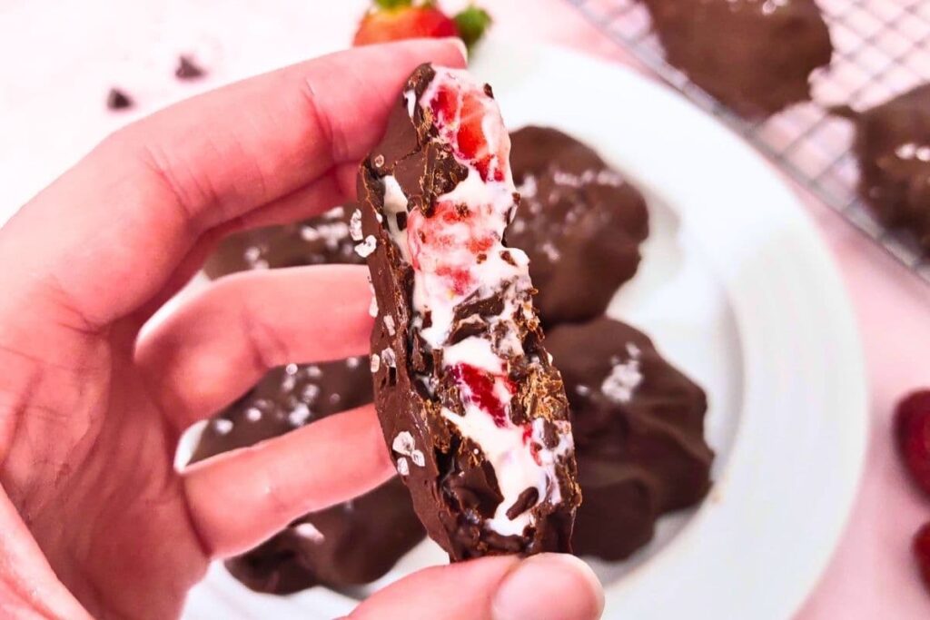 holding up a gooey cross section of a chocolate covered strawberry yogurt cluster